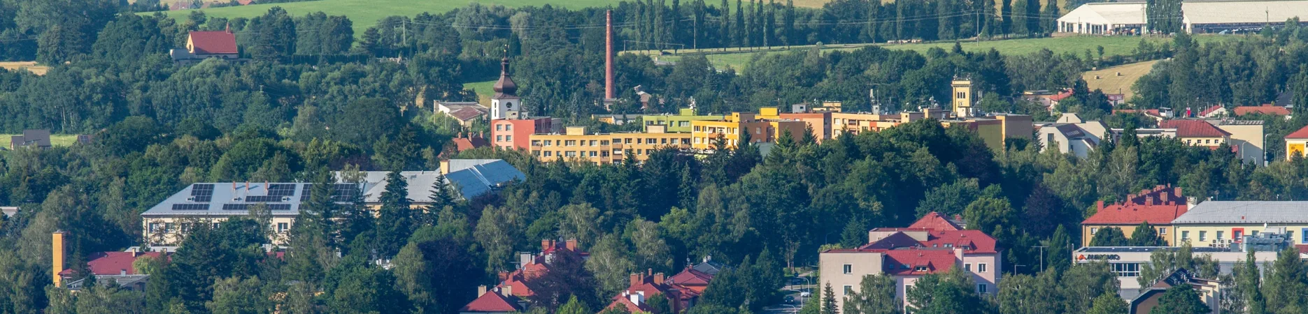 Letecký pohled na frenštátské sídliště s barevnými domy a věží kostela v dálce