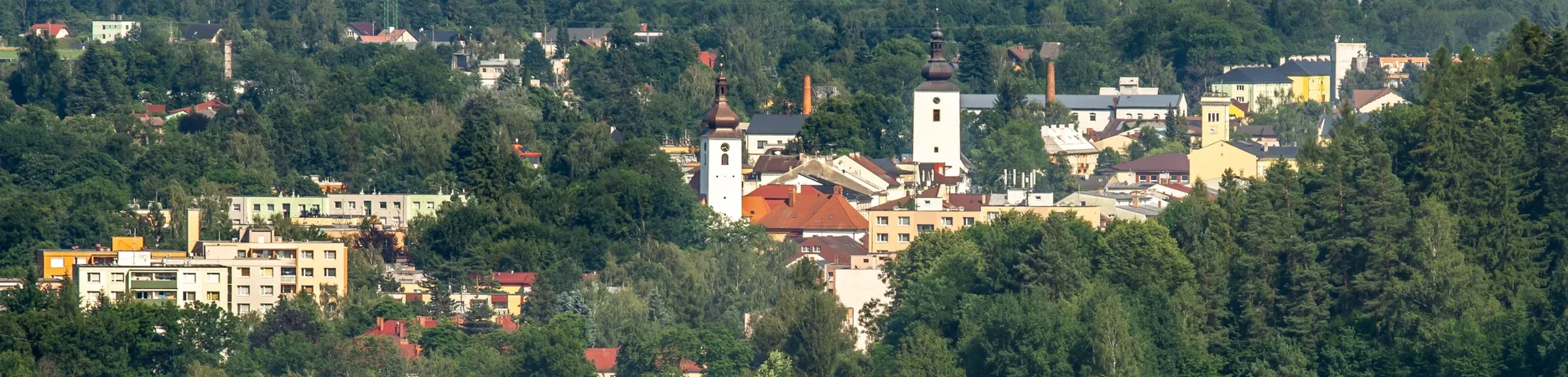 Letecký pohled na Frenštát pod Radhoštěm od jihu, v popředí věž kostela a komíny bývalé továrny